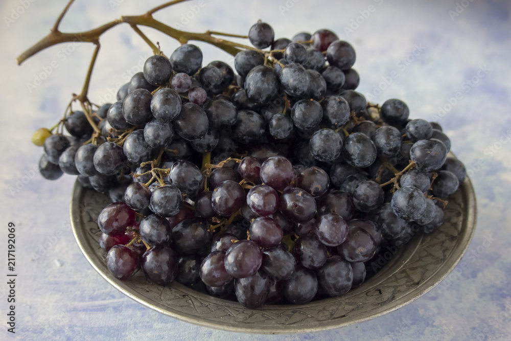 Grapes in silver bowl on the blue background Grapes in silver bowl on the blue background