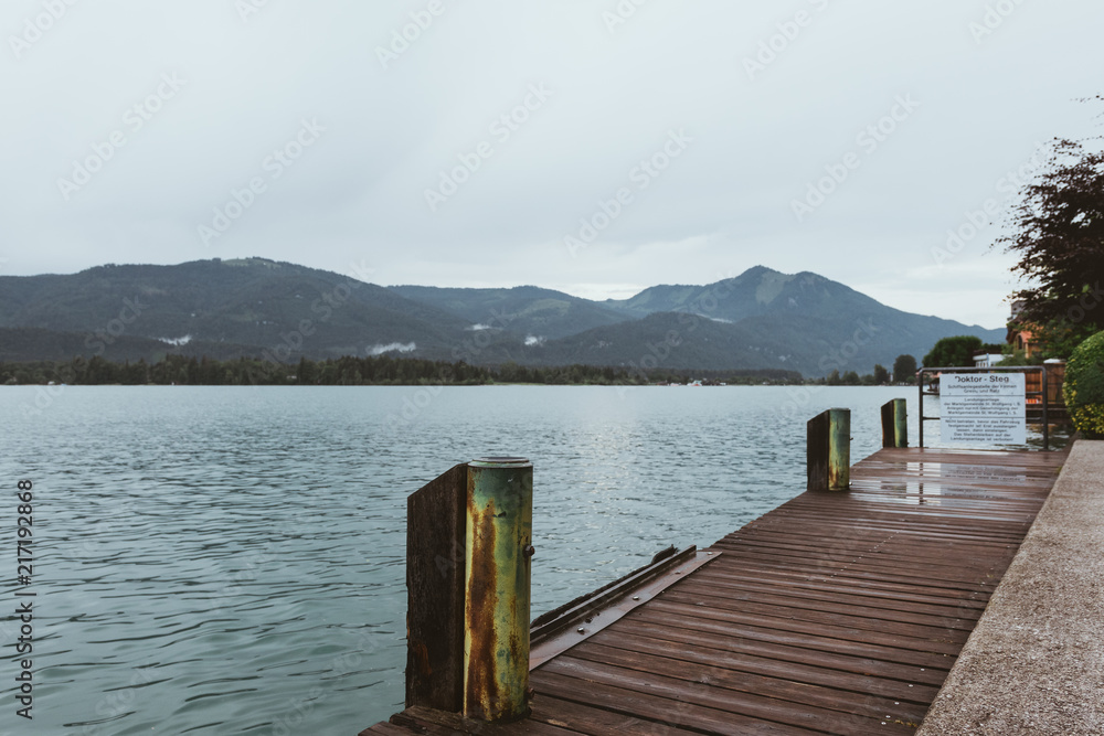 Footbridge at the Wolfgangsee in Austria with mountains in the background and clouds on the sky