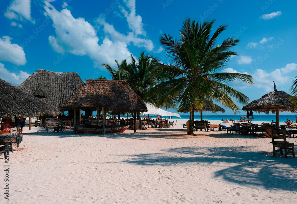 Fototapeta premium Beautiful view of the beach with white sand. People rest on the coast of the Indian Ocean. Zanzibar of Tanzania