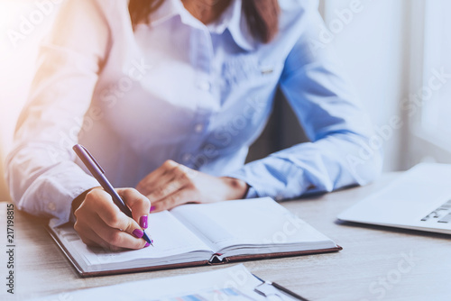 Businesswoman Writing in Notebook in Office .