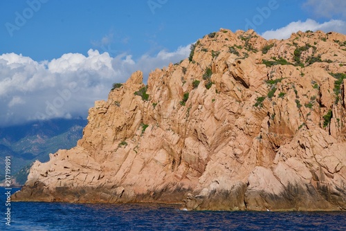 Red rough cliff in the blue ocean