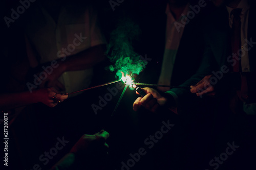 Holiday background with sparklers. Young friends holding bengal lights, closeup, selective focus. Birthday or winter holidays celebration photo