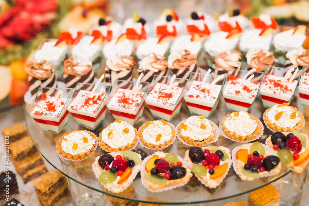 Delicious and tasty dessert table with cupcakes shots at reception closeup