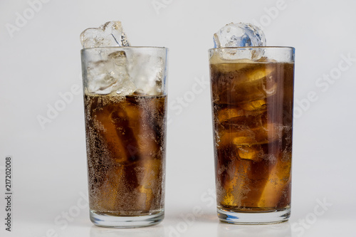 Cold drink with ice in a glass on a white table. A way to cool down on hot days.