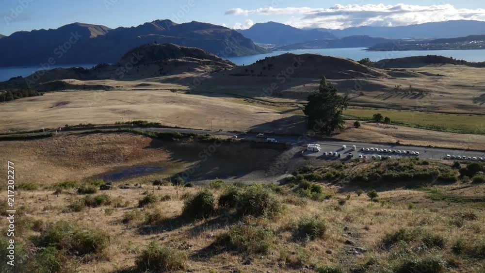Panorama of Lake Wanaka, New Zealand, parking lot at Roy's Peak - campervan passing by Panorama of Lake Wanaka, New Zealand, parking lot at Roy's Peak - campervan passing by