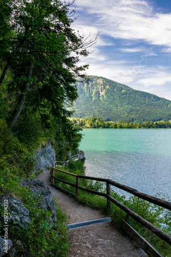 Jetty on the edge of the turquoise lake called Wolfgangsee mountains in the background and clouds on the sky © Christian