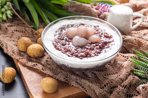Close up soft sweet purple sticky rice pudding, Black Glutinous Rice, with longan and coconut cream on wooden table
