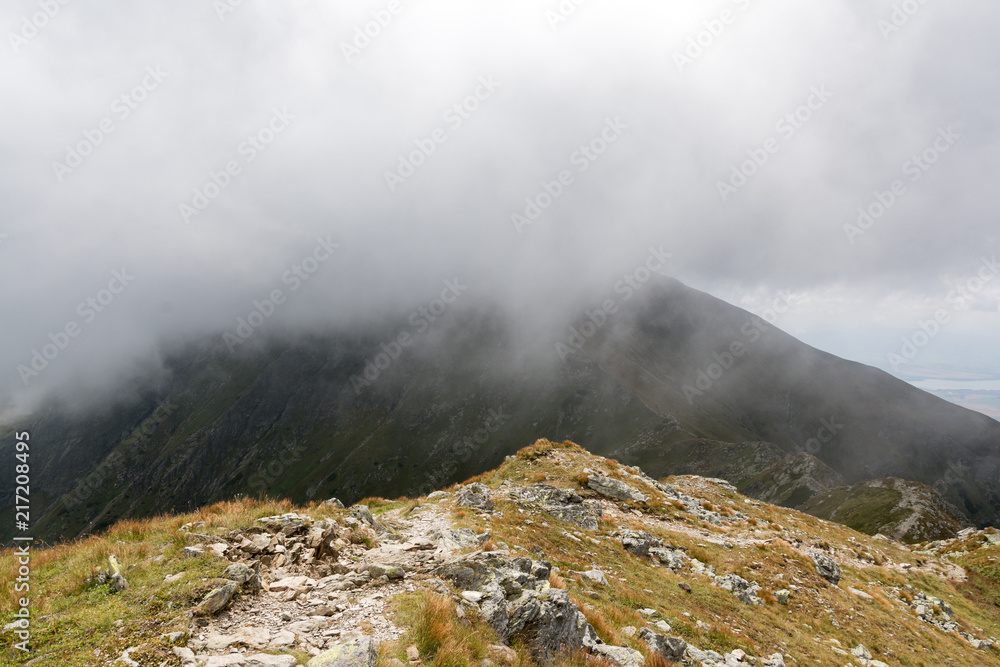 Fototapeta premium mountain ridge covered by half with the cloud
