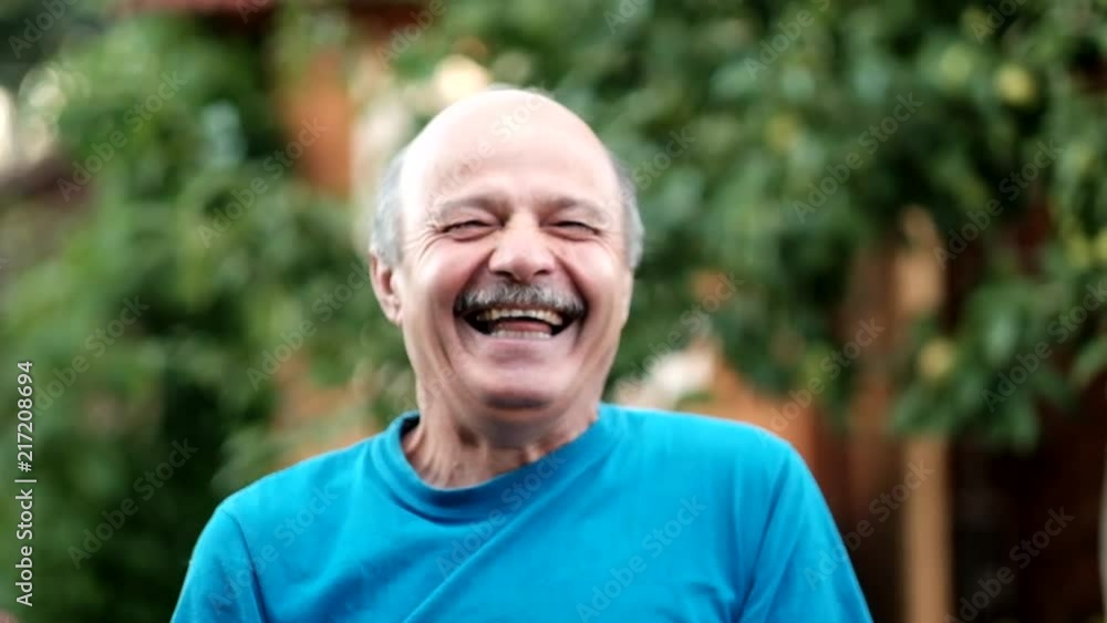 Handsome mature man laughing on background of formal garden in summer day in slow motion Handsome mature man laughing on background of formal garden in summer day in slow motion