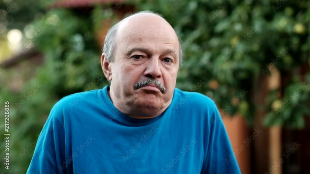Nervous stressed mature man feeling awkward looking with doubt at camera standing on formal garden background. Human emotion face expression feeling body language Nervous stressed mature man feeling awkward looking with doubt at camera standing on formal garden background. Human emotion face expression feeling body language