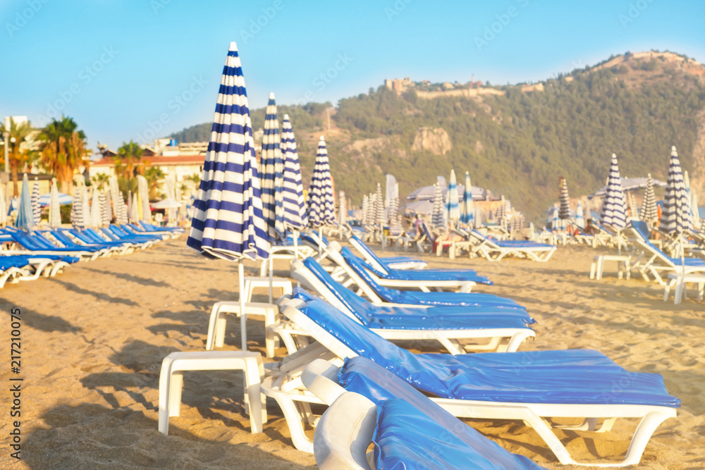 Empty sunbeds with blue mattresses on sandy beach