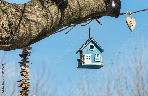 Canvas Print Blue wooden bird house in a tree in the park.