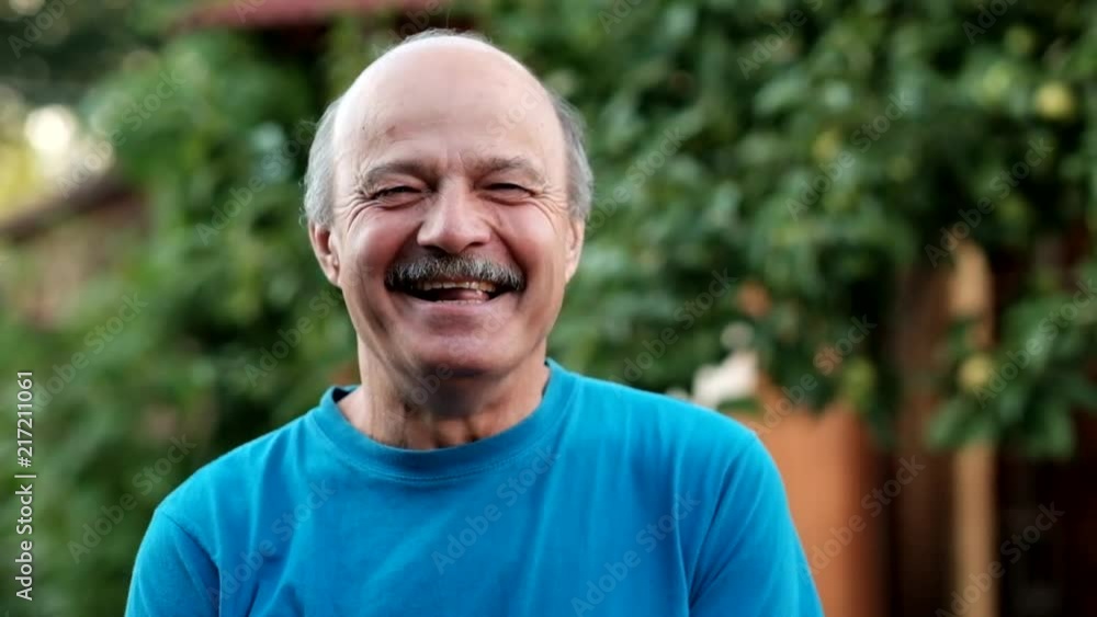 Handsome mature man laughing on background of formal garden in summer day in slow motion Handsome mature man laughing on background of formal garden in summer day in slow motion