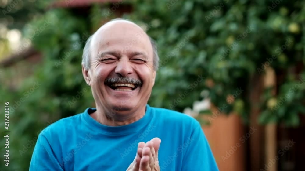 A handsome mature man in blue shirt laughing rubbing hands fairly. Concept of well done work and success A handsome mature man in blue shirt laughing rubbing hands fairly. Concept of well done work and success