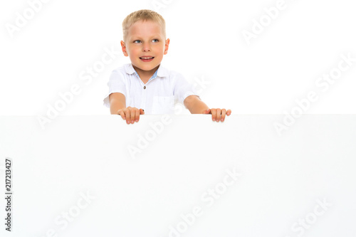 A little boy is looking from behind an empty banner.