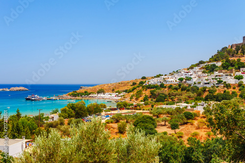 Fototapeta Naklejka Na Ścianę i Meble -  Sea skyview landscape photo Lindos bay and castle on Rhodes island, Dodecanese, Greece. Panorama with ancient castle and clear blue water. Famous tourist destination in South Europe