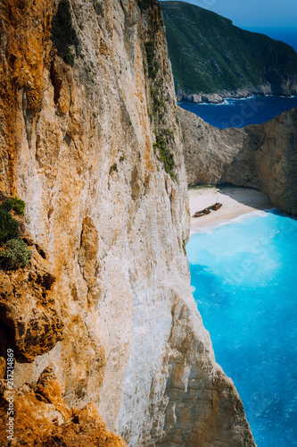 Limestone chalk huge cliff rocks and Navagio beach with abandoned Shipwreck in the distance. Azure blue colored sea. Zakynthos island, Greece photo