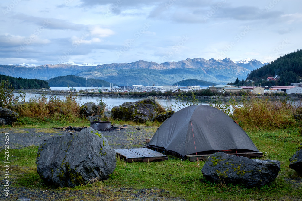 Green tent set in the Cordova campground, Alaska. View of harbor, mountains and ocean. Camping.