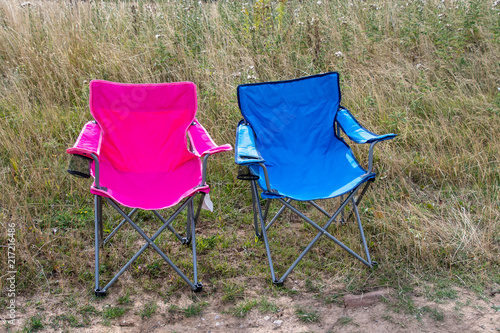 Pink and blue folding camping chairs in a field