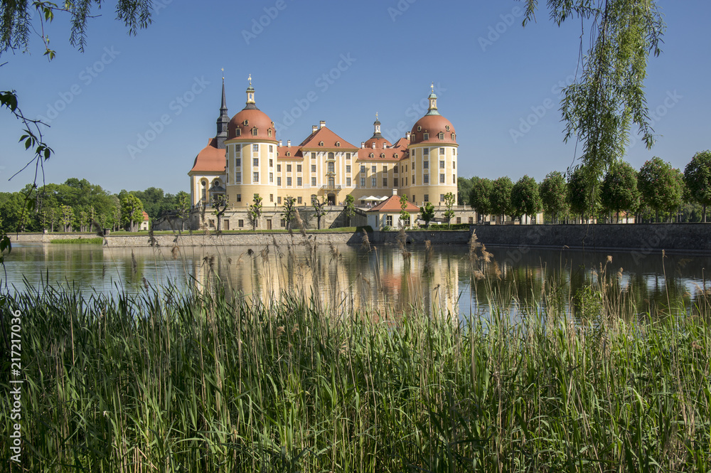 Castle Moritzburg in Saxony near Dresden in Germany surrounded by pond, reflection blue lake, blue sky