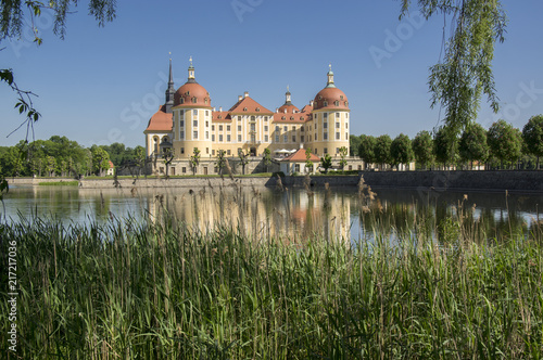 Castle Moritzburg in Saxony near Dresden in Germany surrounded by pond, reflection blue lake, blue sky