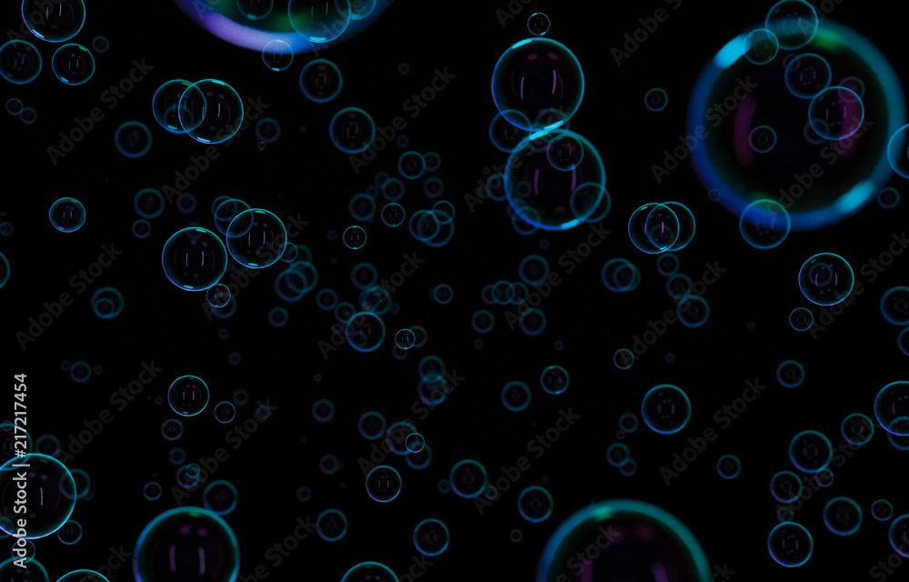 Soap bubbles isolated on black background. Rainbow soap bubble. Bright green and orande colors. 