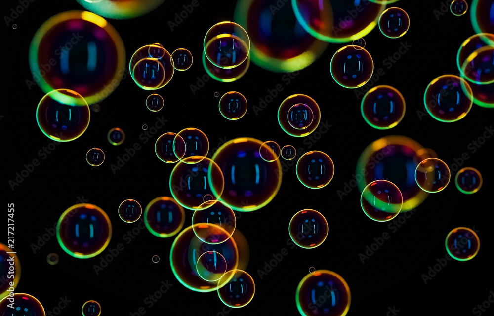 Soap bubbles isolated on black background. Rainbow soap bubble. Bright green and orande colors. 