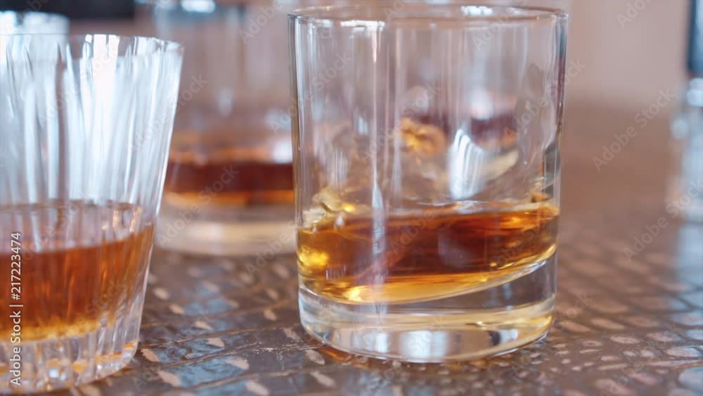 ice falling into a glass of whiskey ice falling into a glass of whiskey