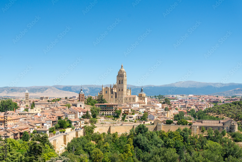 Naklejka premium Scenery of ancient town, old wall and cathedral of Segovia on hill during summer season with blue clear sky in Segovia, Spain