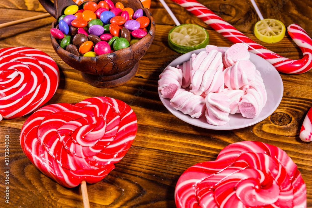 Ceramic plate with marshmallow, candy cane and lollipops on a wooden table Ceramic plate with marshmallow, candy cane and lollipops on a wooden table