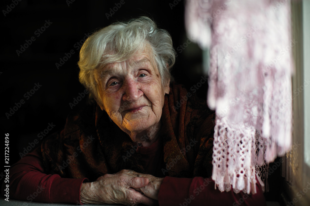 Portrait of an elderly lady sitting in the dark in the house. Portrait of an elderly lady sitting in the dark in the house.