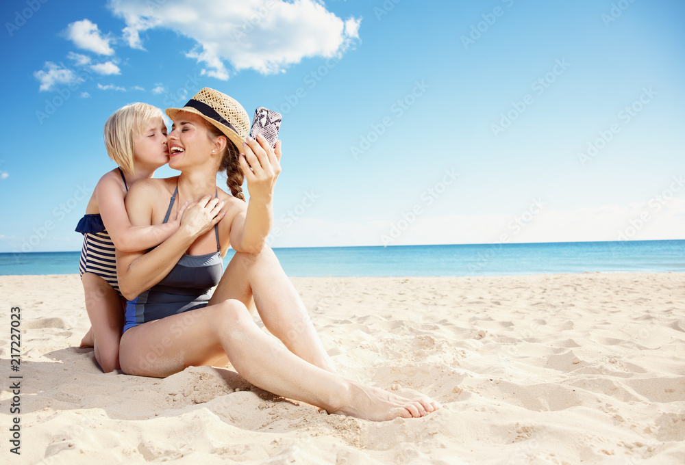 mother and daughter taking selfie with smartphone while kissing mother and daughter taking selfie with smartphone while kissing