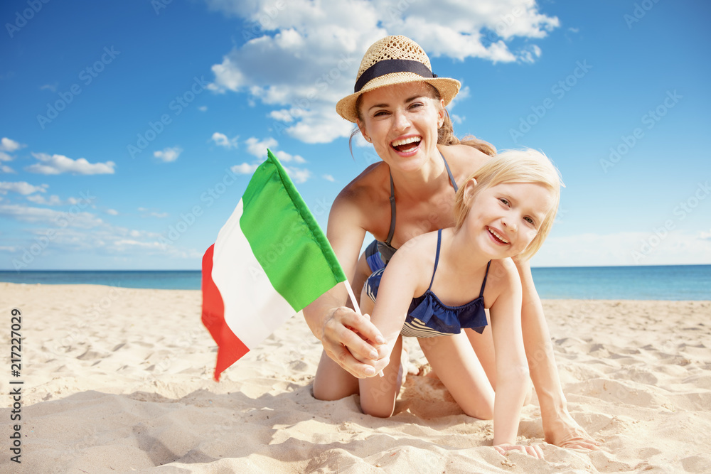happy modern mother and daughter on beach showing Italian flag happy modern mother and daughter on beach showing Italian flag