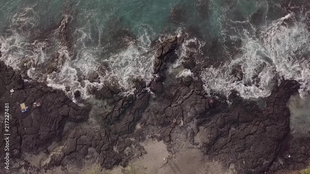 Slow motion overhead view of people relaxing on the rocks at a public beach park on the Big Island of Hawaii. Slow motion overhead view of people relaxing on the rocks at a public beach park on the Big Island of Hawaii.