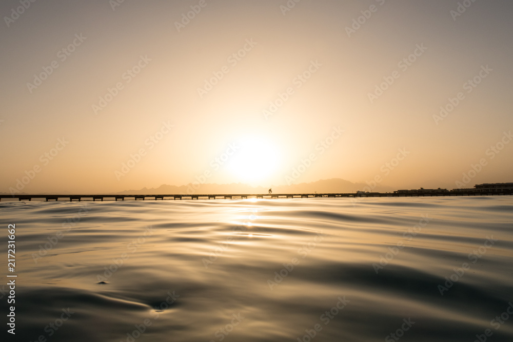 Silhouette of people walking on a jetty in the Sunset from a natural pool on the reef top in the Red Sea, Egypt Silhouette of people walking on a jetty in the Sunset from a natural pool on the reef top in the Red Sea, Egypt