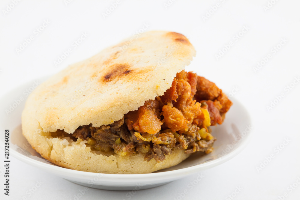 Arepas filled with shredded beef and pork rind served in white dish on white background Arepas filled with shredded beef and pork rind served in white dish on white background