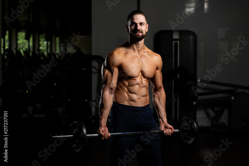 Man In The Gym Exercising Biceps With Barbell