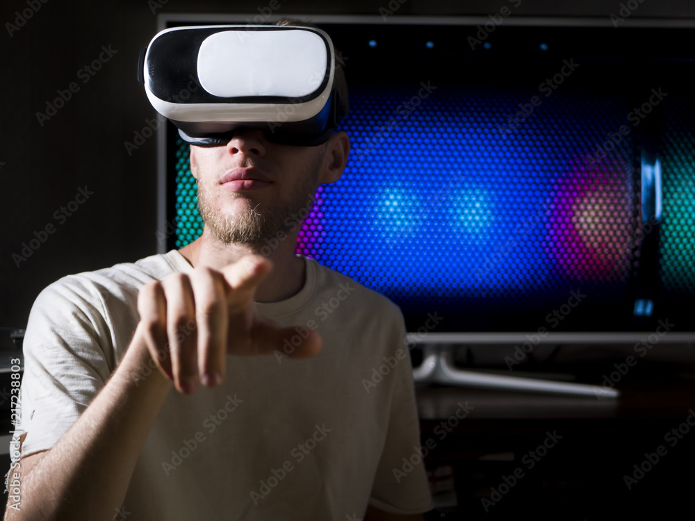 portrait of young handsome bearded man using virtual reality glasses at home in dark room portrait of young handsome bearded man using virtual reality glasses at home in dark room
