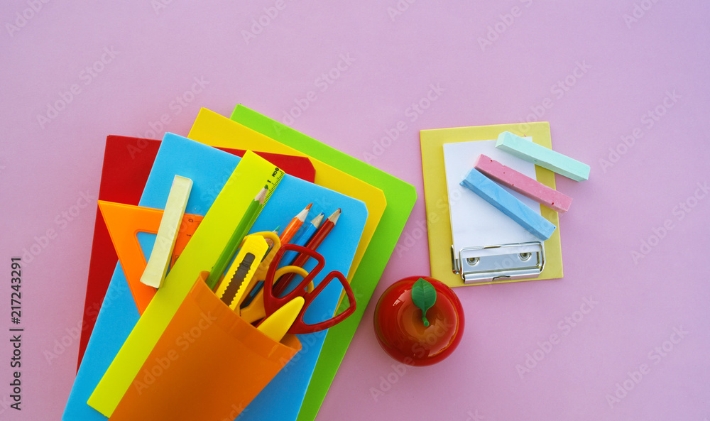 Fototapeta premium The schoolboy's accessories lie on a pink table. Textbooks and office.