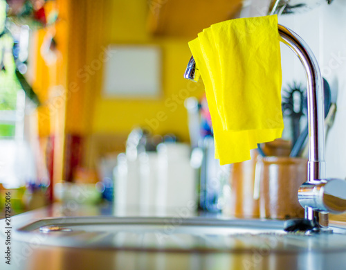 an unhygienic dishcloth hangs over a faucet to dry
