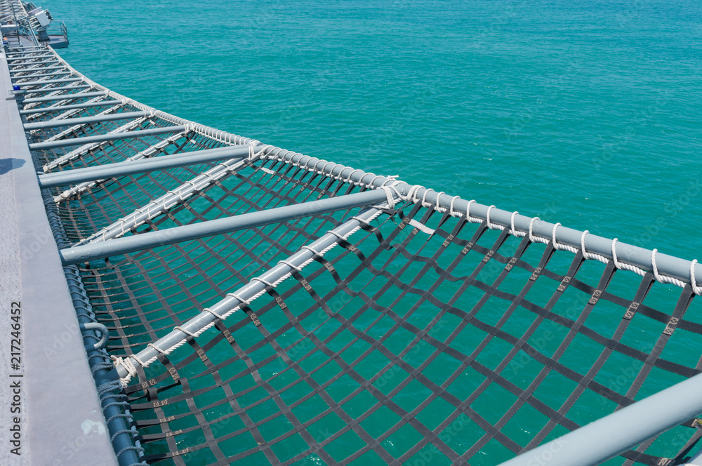 A mesh of battleship on blue sea background .A mesh is a barrier made of connected strands of metal, fiber, or other flexible or ductile materials.