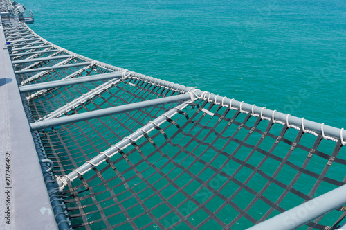 A mesh of battleship on blue sea background .A mesh is a barrier made of connected strands of metal, fiber, or other flexible or ductile materials. © pomchathong007