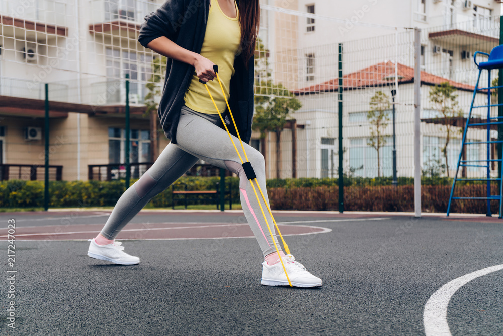 active slender girl doing exercises for leg muscles on a sports field active slender girl doing exercises for leg muscles on a sports field