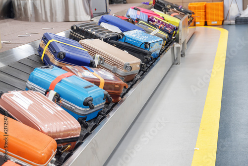 Bright suitcases and bags on luggage conveyor belt in airport photo