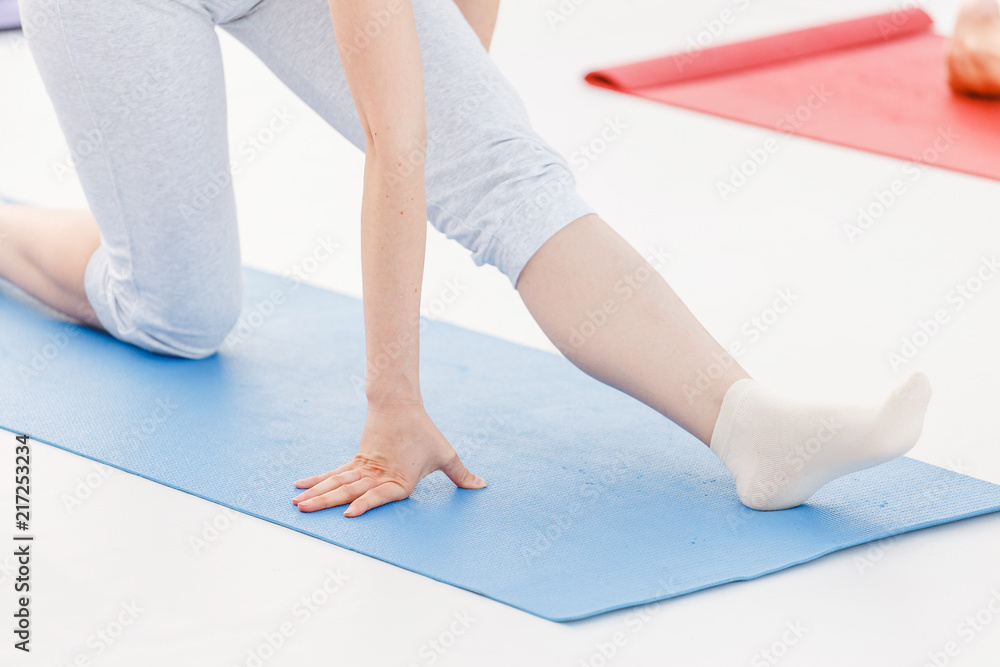 Obraz premium Young sporty woman practicing yoga at class, doing stretching exercise. Close-up detail view of leg and hand