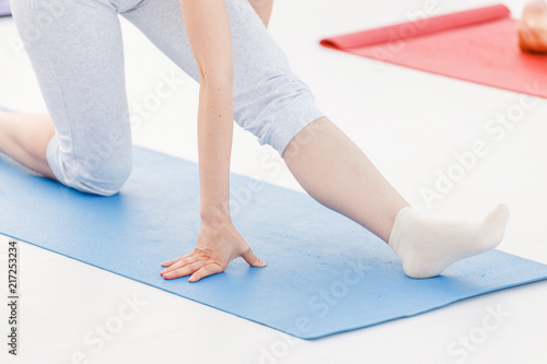 Young sporty woman practicing yoga at class, doing stretching exercise. Close-up detail view of leg and hand