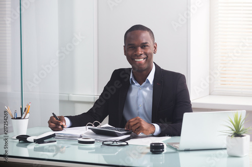 Obraz na płótnie Smiling African Businessman Working At Workplace