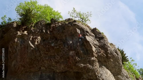 Climber making his way up cliff face with time lapse clouds photo