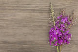 Blooming sally purple flowers with craft paper blank on old grunge wooden background. Top view. Minimalistic mockup.