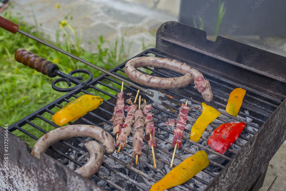 Obraz premium horizontal image with detail of meat of various types and peppers that are cooking on the grill of a barbecue in a garden